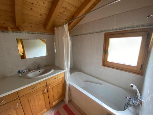 une salle de bain avec une baignoire, un lavabo et un miroir dans l'établissement Chalet calme et spacieux, proche village, navette ski, jardin, animaux acceptés, parking privé - FR-1-624-66, à Samoëns