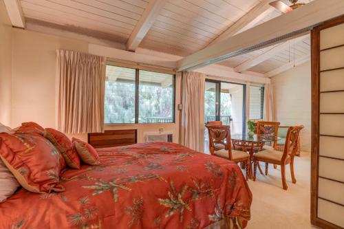 um quarto com uma cama vermelha, uma mesa e cadeiras em Hono Kai C12 em Maalaea