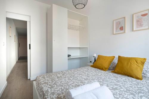 a white bedroom with a large bed with yellow pillows at APARTMENT BEACH PICASSO in Sant Adria de Besos