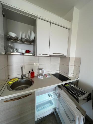 Paradise Apartments Becici في بيشيشي: مطبخ مع حوض ودواليب بيضاء