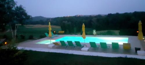 a swimming pool with lawn chairs and umbrellas at Villa "Piemonte" in Tigliole