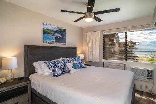a bedroom with a bed with a ceiling fan and a window at Hono Kai A5 in Wailuku