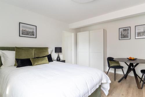 a white bedroom with a bed and a table at Green Flat Düsseldorf First in Düsseldorf