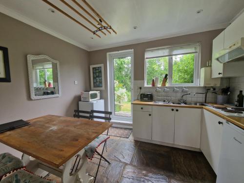 cocina con armarios blancos y mesa de madera en Molly Dishwasher Shepherds Hut en Frant