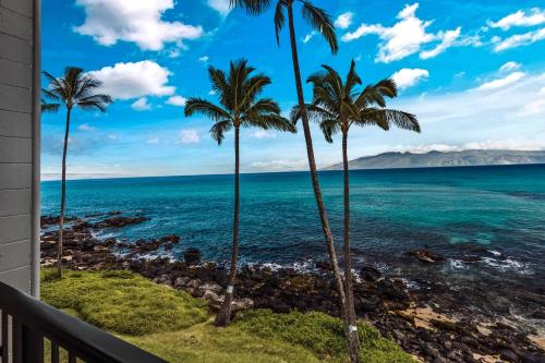 d'un balcon avec des palmiers offrant une vue sur l'océan. dans l'établissement Noelani 309, à Kahana