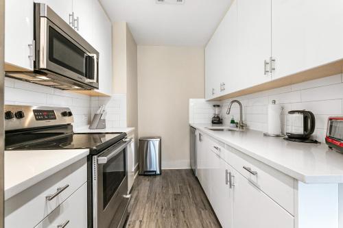 a kitchen with white cabinets and a microwave at Elegant Studio Near French Quarter in New Orleans