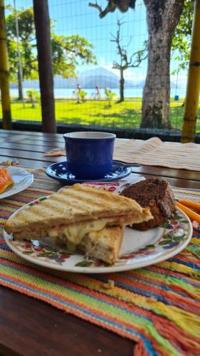 a plate of food with a sandwich on a table at Hostel Na Praia - Hospedagens e eventos in Ubatuba