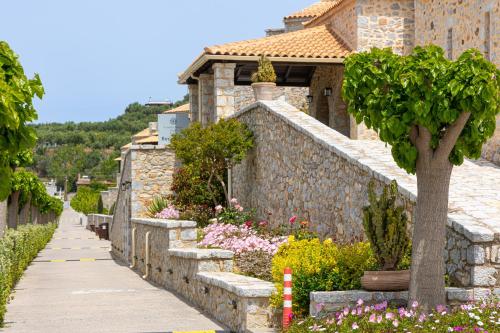 a walkway in front of a stone wall with a tree at Castello Antico Hotel in Gythio