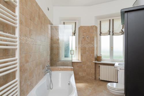 a bathroom with a bath tub and a toilet at MONFERRATO HILLS Charming Garden Villa in Vignale Monferrato