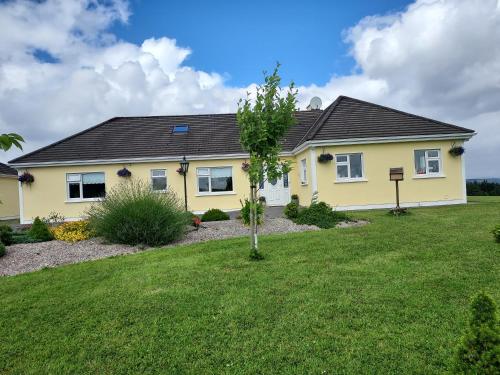 a yellow house with a tree in the yard at Tullaleagan Guesthouse in Oughterard