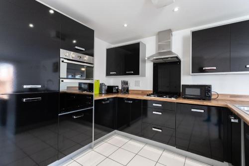 a kitchen with black cabinets and wooden counter tops at April Disc - Long Stay - Contractors in Bristol