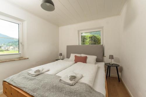 Un dormitorio blanco con una cama grande con toallas. en Kesselgrubs Apartements Ski & Badeglück, en Eben im Pongau