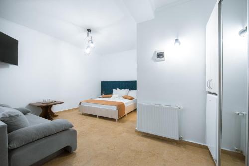 a white bedroom with a bed and a couch at Vila Puky in Neptun