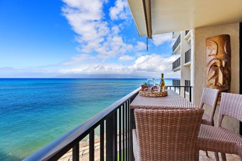 a balcony with a table and chairs and the ocean at Hololani A402 in Kahana