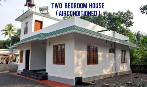 a white house with the words two bedroom house air conditioned at Kuttickattil Gardens Homestay in Kottayam