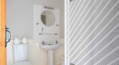 een badkamer met een wastafel, een toilet en een spiegel bij Ullswater in Sawrey