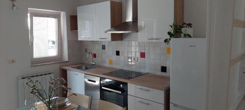 cocina con armarios blancos y nevera blanca en Apartma Vida, en Koper