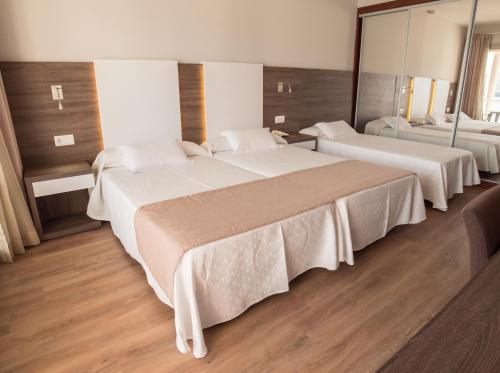 a hotel room with two beds with white sheets at Seramar Hotel Comodoro Playa in Palmanova