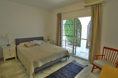 a bedroom with a bed and a window and a chair at Villa Golondrinas - Private villa to sleep 6 in Nerja