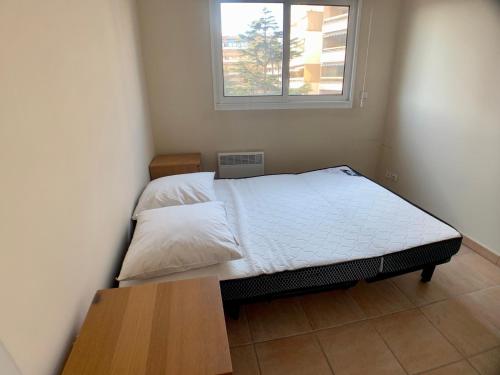 ein kleines Bett in einem Zimmer mit Fenster in der Unterkunft Appartement Hesperides avec Terrasse in Cannes