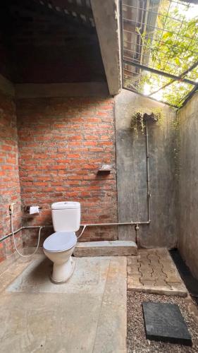 a bathroom with a toilet in a brick wall at Nongu Home in Trincomalee