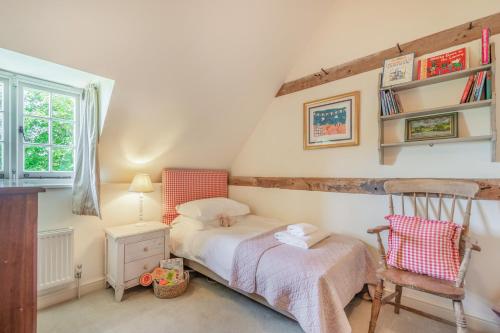 a bedroom with a bed and a chair and a window at Beachy Barn in Eastdean