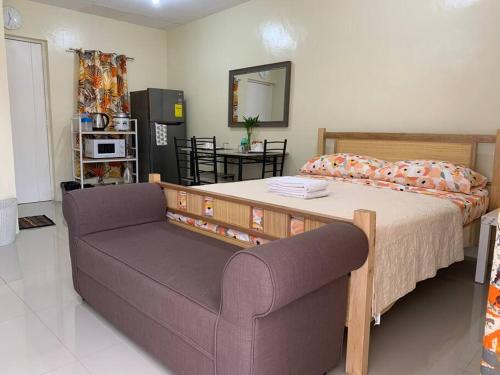 1 dormitorio con cama, sofá y espejo en A comfy retreat in the heart of Orani, Bataan en Orani