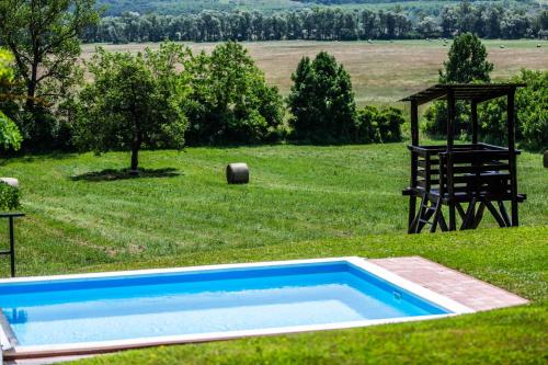 a blue swimming pool in a field with a gazebo at Oszter-ház Kékkút in Kékkút