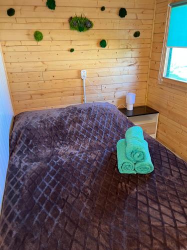 a bedroom with a bed with green towels on it at Swojskie Chatki - Leśna Chatka in Smołdziński Las