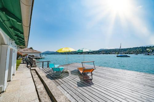 a wooden dock with chairs on the water at Villa Fernblick in Velden am Wörthersee
