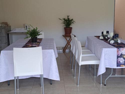 a dining room with two tables and white chairs at Jate Guest House in Maseru