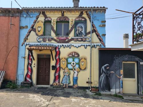 un mural en el lateral de una casa con niños parados delante en Domus Claudia, en Castiglione in Teverina