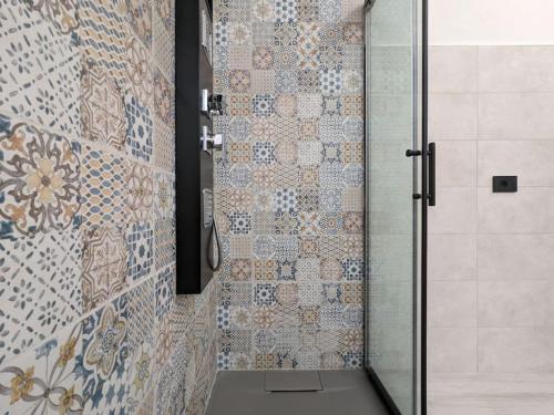 y baño con ducha y azulejos azules y blancos. en Santeria Modern Loft en Tortolì