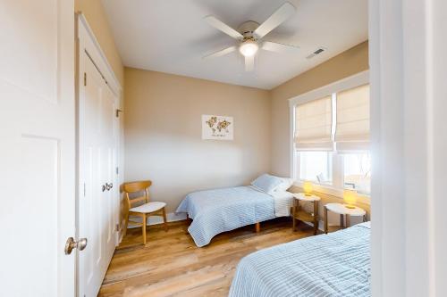 1 dormitorio con 2 camas y ventilador de techo en Pawsitive Island Escape, en Oak Island