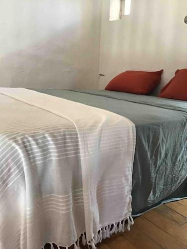 - un lit avec une couverture blanche et des oreillers rouges dans l'établissement Uzès proche,charmant pied a terre avec terrasse, à La Bastide-dʼEngras