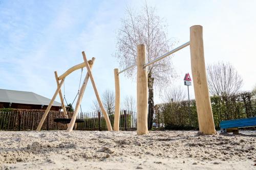 a wooden playground in the sand with a bench at Glamping Valkenburg in Meerssen