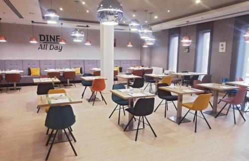 a dining room with tables and chairs and a sign that reads dine all day at Holiday Inn Trnava by IHG in Trnava