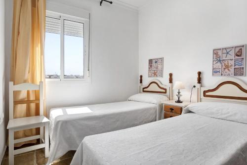 biały pokój z 2 łóżkami i oknem w obiekcie Indico 210 w mieście Conil de la Frontera