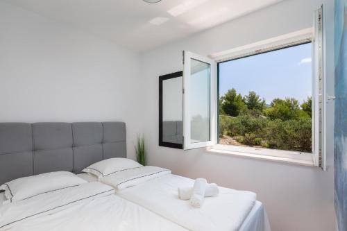 a white bedroom with a bed and a window at Sunrise Apartment Hvar in Hvar