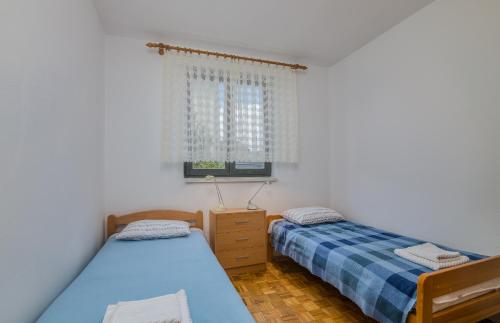 two twin beds in a room with a window at Apartment Dinka in Čižići