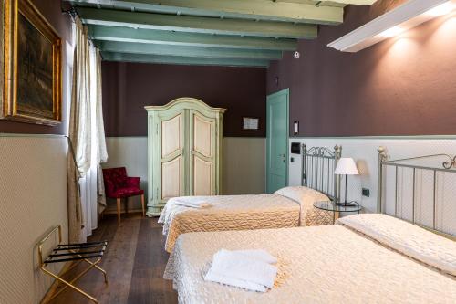 Habitación con 3 camas y silla roja. en Residenza Villa Vecelli Cavriani, en Mozzecane