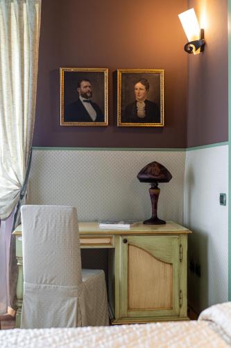 a bedroom with two portraits on the wall and a desk at Residenza Villa Vecelli Cavriani in Mozzecane