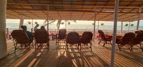 a group of people sitting at a table on the beach at Anthy’s Guesthouse and Restaurant in Benaulim