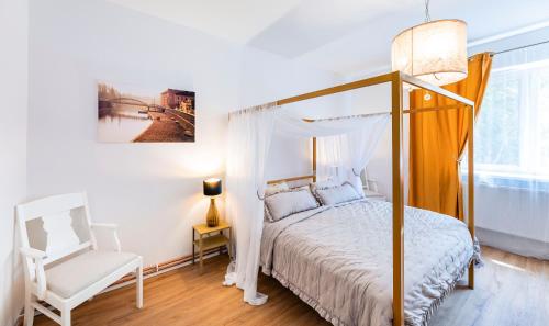 een slaapkamer met een hemelbed en een witte stoel bij Silvie Apartments - Masaryk dolní in Olomouc