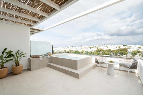 a bathroom with a tub and a balcony with a view at Aura Suites Paros in Naousa
