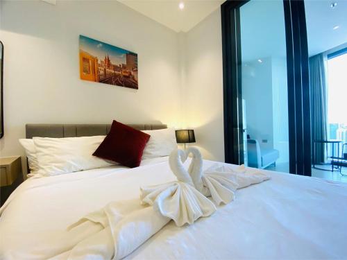 a bedroom with a white bed with a towel on it at Edge Central Pattaya Vip Condo in Pattaya Central