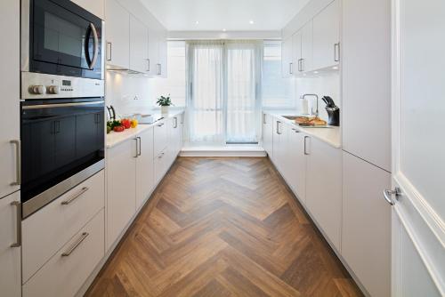a kitchen with white cabinets and a wooden floor at Cheval Knightsbridge in London