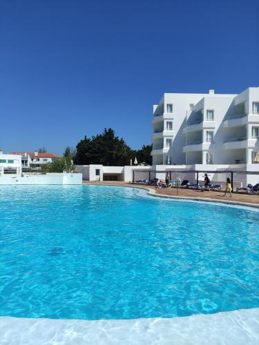 a swimming pool with blue water in front of some buildings at Prainha Clube in Alvor