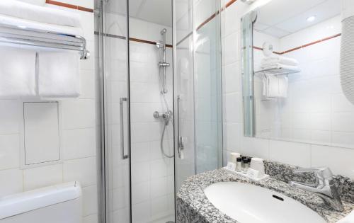 ein Bad mit einem Waschbecken und einer Dusche in der Unterkunft Hôtel Marais de Launay in Paris