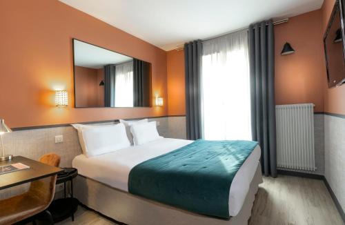 a hotel room with a bed and a table and a mirror at Hôtel Marais de Launay in Paris